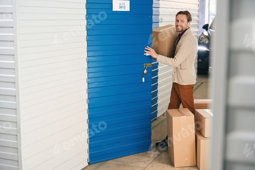 Preview: Young man with big cardboard boxes in self storage unit
