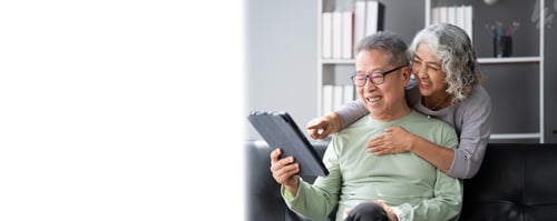 Visualização: Feliz casal asiático maduro usando um tablet digital na sala de estar, passando tempo e se relacionando com cada um