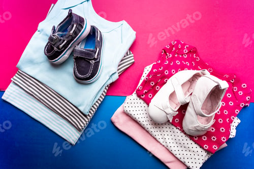 Preview: Folded blue and pink bodysuit. Stack of infant clothing. Child outfit.