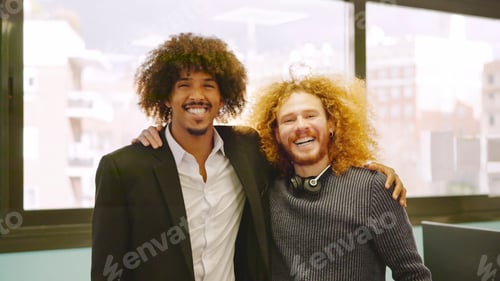 Preview: Coworkers with curly hair embracing in the office
