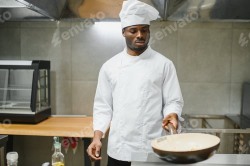 Preview: African American male chef standing at kitchen counter in restaurant kitchen, copy space