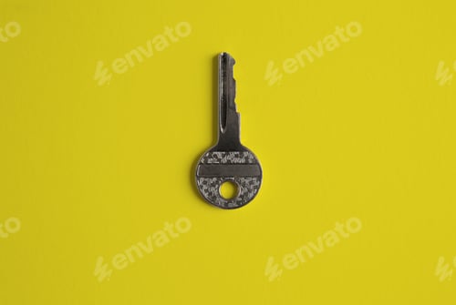 Preview: Door key in center of empty yellow background. Top view.