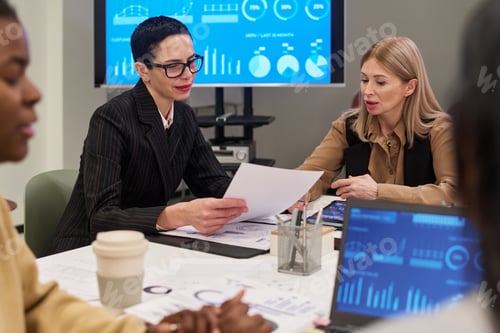 Preview: Middle Aged Caucasian Woman Discussing Business Report with Colleagues
