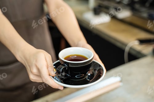 Preview: Asian Barista waiter handing a cup of hot coffee to customer at cafe.