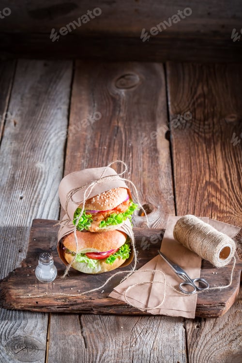 Preview: Fresh takeaway hamburger wrapped in paper on old wooden table