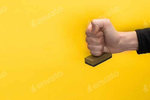 Preview: cropped view of man holding stamp isolated on yellow, quality concept