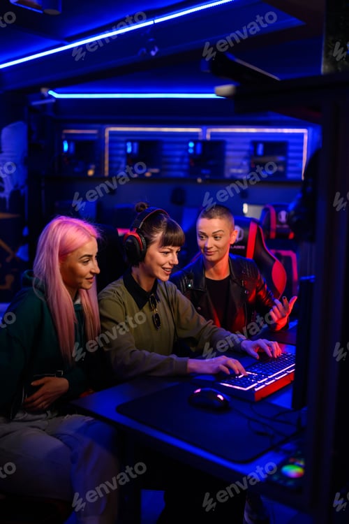 Preview: Three female friends gamers playing online video game in an internet cafe