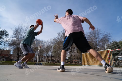 Preview: Two friends playing basketball outdoors on a sunny day