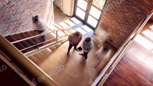 Aperçu: Two Male Business Colleagues With Digital Tablet Having Informal Meeting By Stairs In Busy Office