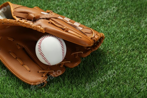 Preview: Catcher's mitt and baseball ball on green grass, space for text. Sports game