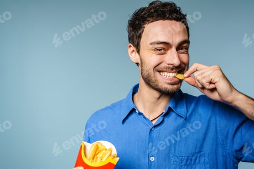 Preview: Happy handsome guy smiling while eating french fries