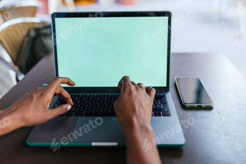 Preview: Afroamerican woman typing on laptop in a cafe