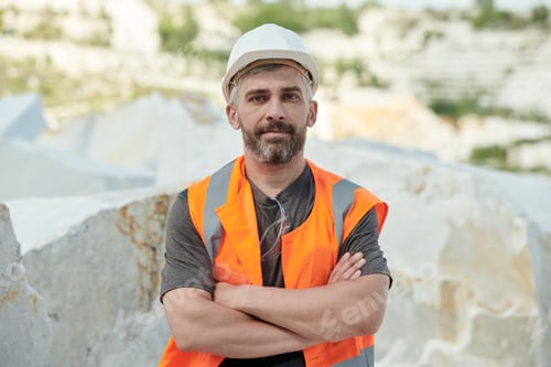 Preview: Confident mature foreman in hardhat and workwear crossing arms on chest