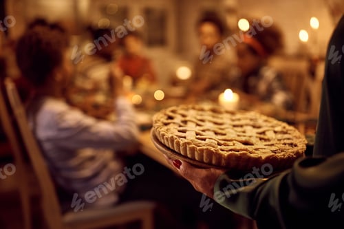 Preview: Close up of woman serving sweet pie during Thanksgiving meal with her family in dining room.
