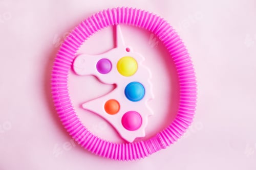 Preview: Simple dimple in the form of unicorn and a tube fidget toy on a pink background.