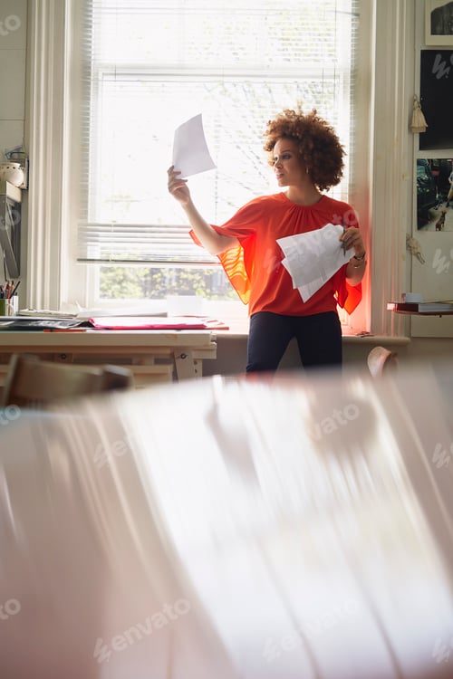 Preview: Creative professional reviewing paperwork in a sunlit home office.