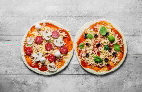 Preview: Two Uncooked Pizza Pies with Toppings