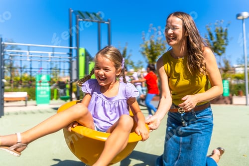 Preview: Mother and daughter playing and having fun in playground