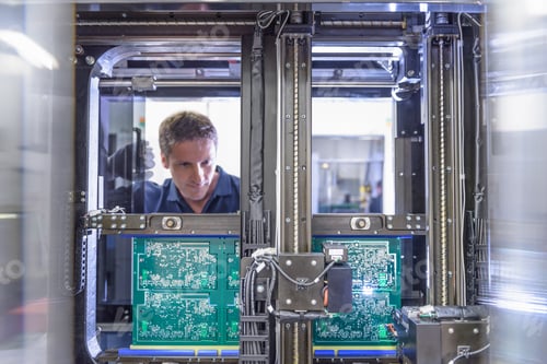 Preview: Worker loading circuit boards into testing machine in circuit board factory