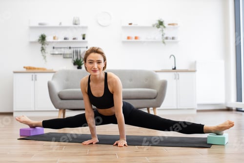 Preview: Woman practicing yoga splits at home in bright living room