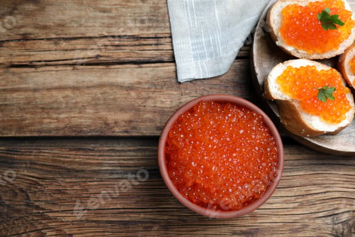 Preview: Bowl with delicious red caviar and tasty sandwiches on wooden table, flat lay. Space for text