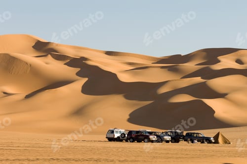 Preview: Caravan of offroad vehicles at rest in the expansive desert dunes.