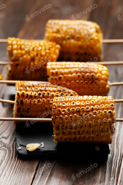 Preview: Slate tray with Pieces of Grilled corn on the cob on kitchen table healthy food background