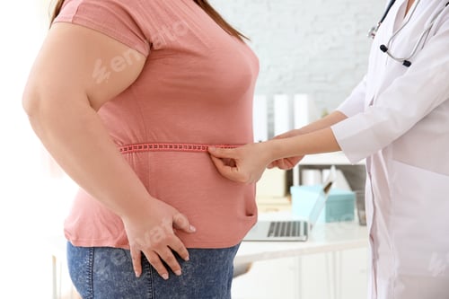 Preview: Female doctor measuring waist of overweight woman with measuring tape in clinic