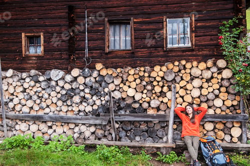 Preview: Austria, Altenmarkt-Zauchensee, young female hiker having a rest in front of Alpine cabin