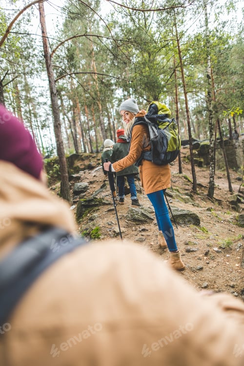 Preview: selective focus of smiling woman looking at camera while trekking together with family in autumn