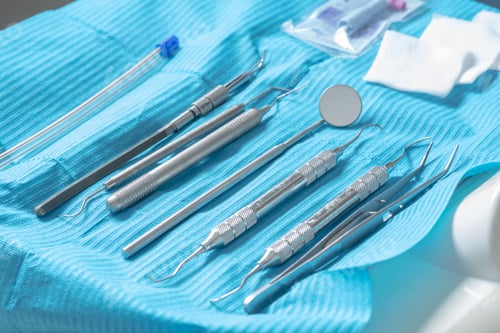 Preview: Closeup shot of professional dental instruments for treatment on a blue surface