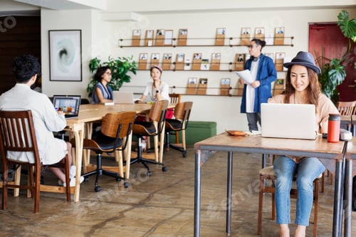 Preview: Group of young Japanese professionals working on laptop computers in a co-working space.