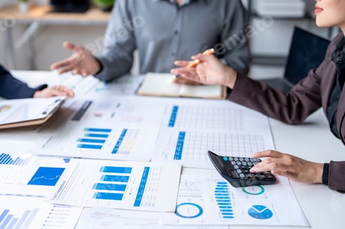 Preview: Business team analyzing financial documents and using calculator in office meeting