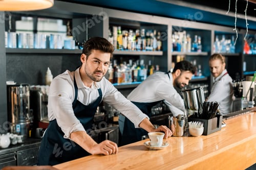 Preview: adult handsome barista in apron with coffee at wooden counter