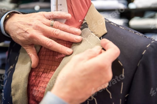 Preview: Tailor preparing bespoke suit jacket on tailors dummy, close up of hands