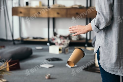 Preview: cropped view of shocked woman dropping paper cup at robbed home