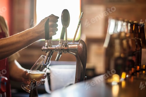 Preview: Hands of bartender pulling beer pump