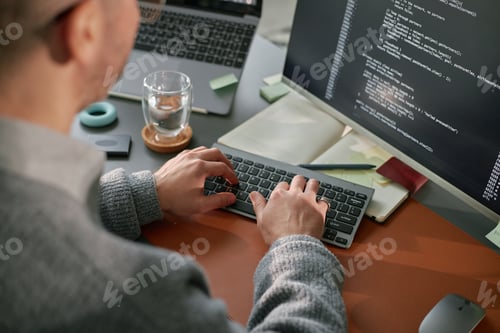Preview: Young Adult Caucasian Man Coding Software on Computer in Modern Office Setting