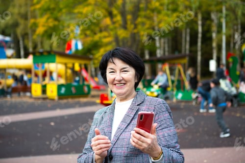Preview: Portrait of a happy senora for 50 years in the park in autumn in a gray jacket