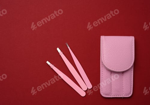 Preview: Pink leather case with various metal eyebrow tweezers on a red background