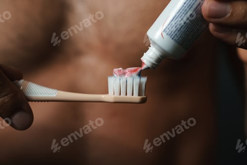 Preview: Cropped photo of young half-naked man brushing his teeth