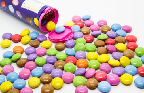 Preview: Multicolored glazed chocolate candies out of the container