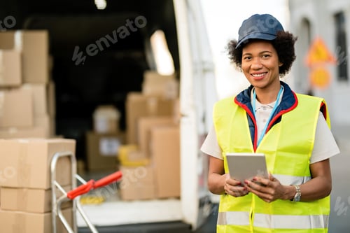 Preview: Happy African American deliverer with digital tablet in the city.