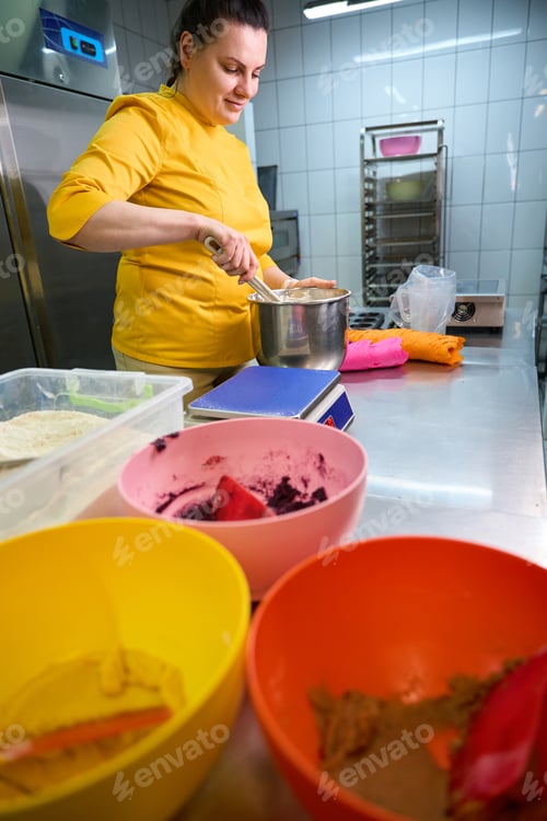 Preview: Smiling female baker is making pastry dough