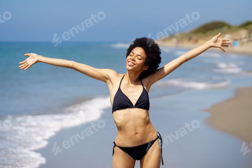 Preview: Positive African American female in swimwear standing with outstretched arms and closed eyes on
