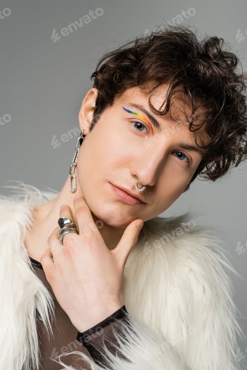 Preview: portrait of pansexual model with wavy brunette hair and rainbow eye liner looking at camera isolated