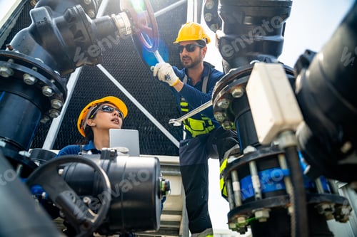 Preview: Two technicians in hard hats and safety vests working on industrial cooling tower pipes