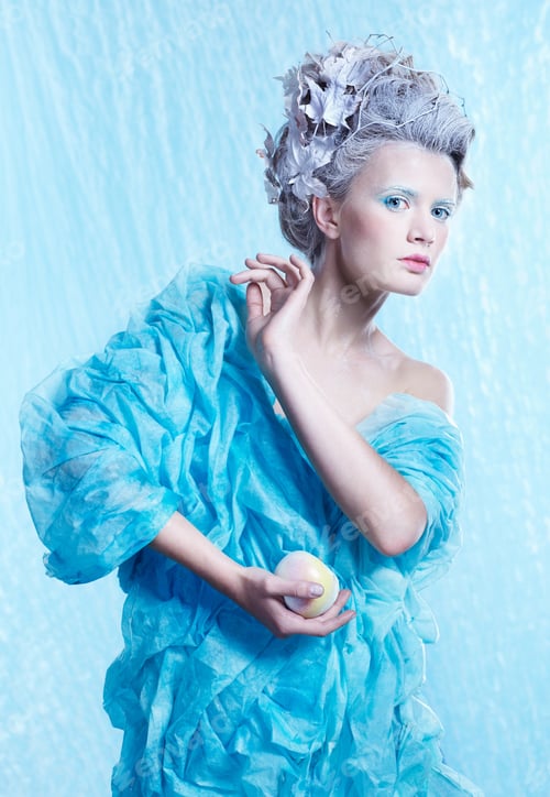 Preview: Fantasy Portrait Of Beautiful Young Woman Imaging Ice Fairy With Frozen Apple On Blue