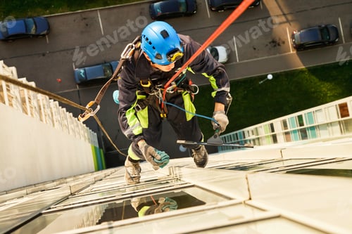 Preview: Urban Climber Skillfully Washes Glass Facade High Above City Streets During Bright Daylight