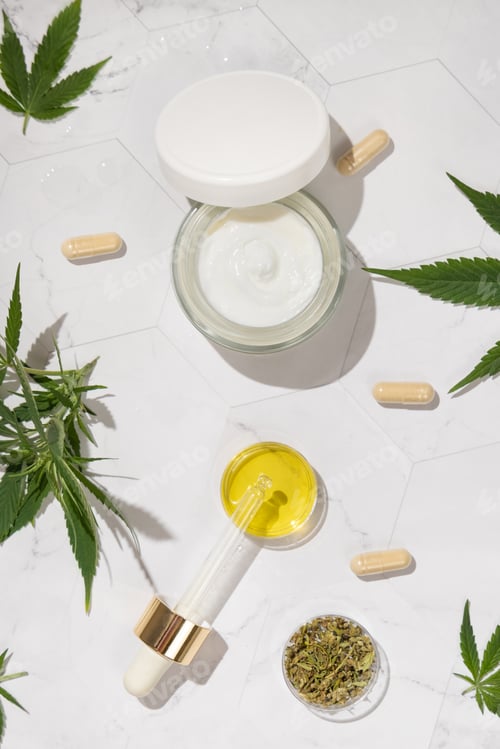 Preview: Cram jar, Pipette with CBD oil, capsules and Tea near green cannabis leaves. Alternative medicine